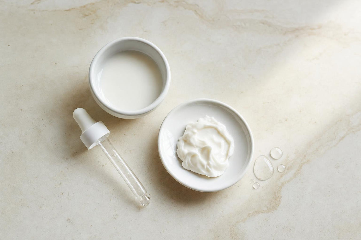 Cuenco con leche, gotero y crema sobre piedra clara